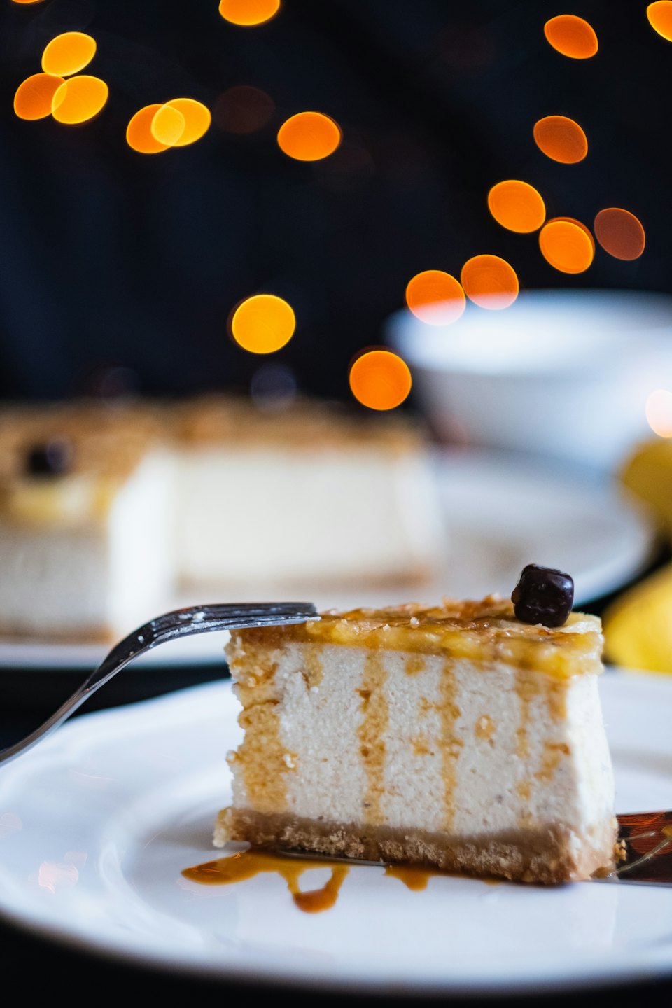 A slice of caramel cheesecake with a silver fork on a plate.