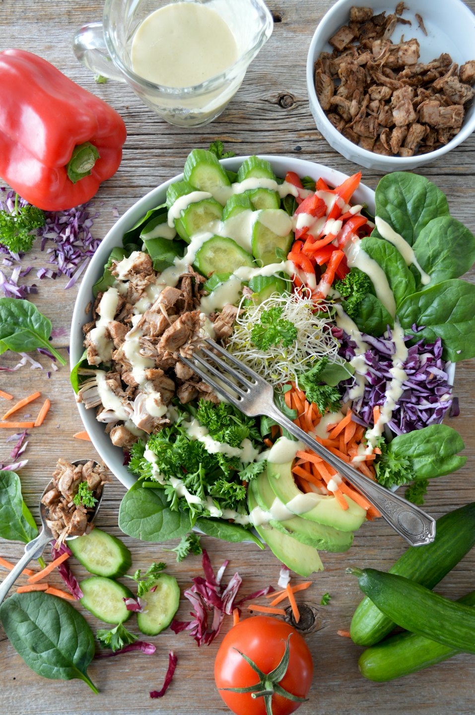 Fresh salad with meat and vegetables in a white bowl on wood.